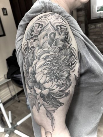 Japanisches Cover-up Tattoo am Oberarm in Black and Grey mit großer Chrysantheme und asiatischen Ornamenten, professionelles Tattoo Cover-up von Sabine Jacobs im Talisman Tattoo Studio in Raeren, spezialisiert auf hochwertige Custom Tattoos nahe Aachen, Eupen und Ostbelgien.