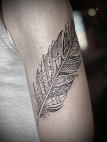 Feines Feder Tattoo in Blackwork und Dotwork mit geometrischen Mustern und filigranen Linien, elegantes Fine Line Tattoo am Oberarm, modernes minimalistisches Custom Tattoo mit strukturierter Federoptik, individuell entworfen von Sabine Jacobs im Talisman Tattoo Studio in Raeren – professionelles Tattoo Studio für hochwertige Fine Line und Dotwork Tattoos nahe Aachen, Eupen und Ostbelgien.