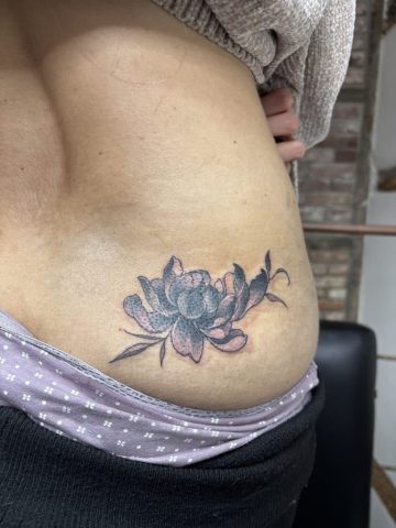 Florales Cover-Up Tattoo in Black & Grey auf der Hüfte zum Überdecken eines alten Namens Tattoos.