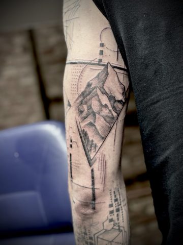 Geometrisches Tattoo mit Bergen, Wald und abstrakten Linien in Black & Grey.