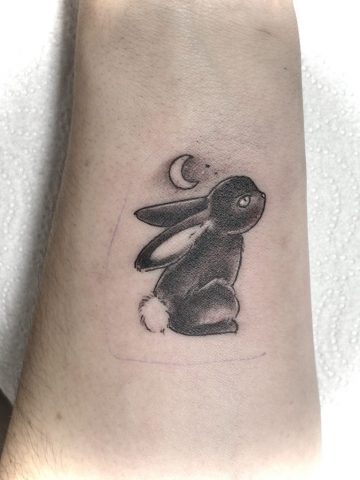 Hasen Tattoo in Black & Grey mit Mond, niedliches Tier Tattoo am Unterarm mit weichen Schattierungen, verspieltes Fineline Illustrations Tattoo, gestochen bei Talisman Tattoo – Sabine Jacobs, exklusives Tattoo Studio in Raeren, Belgien nahe Aachen, NRW, Eupen, Sankt Vith, Luxemburg, Europa, internationale Tattoo Kundschaft