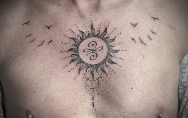 Feines Fineline Brust Tattoo mit spiritueller Sonne, ornamentalem Kreis und persönlichem Symbol im Zentrum, symmetrisches Tattoo auf der Brust mit zarten Linien und energetischer Bedeutung, minimalistisches Sacred Tattoo Design mit Balance und Schutzsymbolik, individuelles Custom Tattoo gestochen bei Talisman Tattoo – Sabine Jacobs, Tattoo Studio in Raeren, Belgien, nahe Aachen, NRW, Eupen, Sankt Vith und Luxemburg, spezialisiert auf hochwertige Fineline Tattoos, spirituelle Tattoos und exklusive Einzelanfertigungen