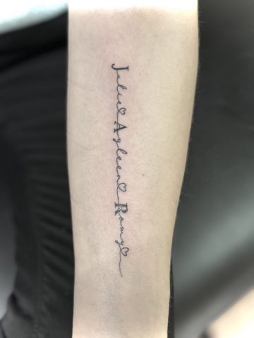 Filigranes Lettering Tattoo mit Familiennamen in feiner Handschrift auf dem Unterarm.