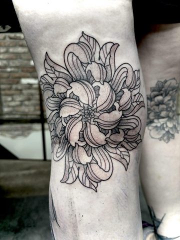 Ornamentales Blumen Tattoo im Mandala-Stil auf dem Knie. Symmetrisches Black & Grey Design mit feinen Linien, dekorativen Blütenblättern und harmonischer Dotwork-Schattierung.