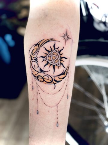 Sonne Mond Tattoo mit keltischem Knoten, Stern und Dotwork-Elementen als symbolisches Fine Line Tattoo am Unterarm.
