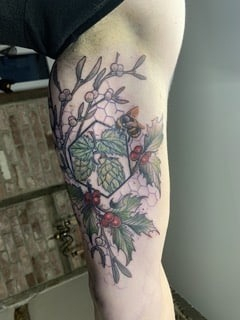 Aufgefrischtes Natur Tattoo mit Biene, Blättern, Beeren und floralen Elementen nach einem professionellen Tattoo Touch-Up.