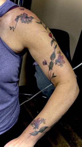 Farbiges Blumenranken Tattoo mit zarten Blüten und feinen Linien als florales Arm Tattoo.